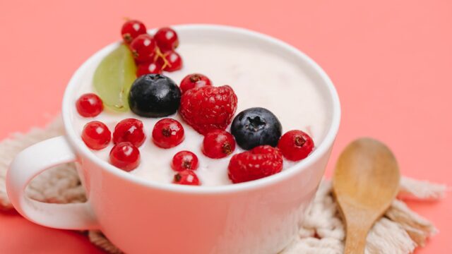 tasty healthy dessert with berries served on pink table with wooden spoon